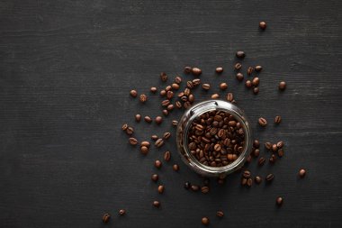 Koyu yüzeyde kahve çekirdekleri ile dolu cam kavanoz üst görünümü