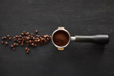 Top view of portafilter with coffee on dark wooden surface with scattered coffee beans clipart
