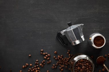 Kahve çekirdekleri ile koyu ahşap yüzeyüzerinde kaşık ve cam kavanoz yakın gayzer kahve makinesi parçaları üst görünümü