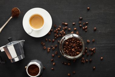 Gayzer kahve makinesi, kahve çekirdekleri ile koyu ahşap yüzeyüzerinde kahve ve kaşık yakın kahve çekirdekleri ile cam kavanoz üst görünümü