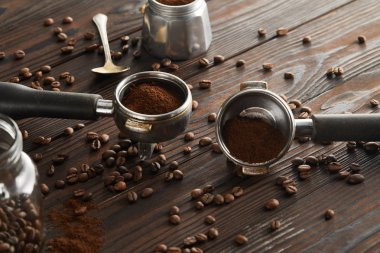 Koyu ahşap yüzeyüzerinde kaşık, cam kavanoz ve gayzer kahve makinesi yakınında Portafilters