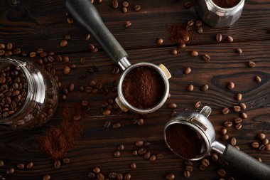 Koyu ahşap yüzeyüzerinde cam kavanoz ve gayzer kahve makinesi arasında Portafilters