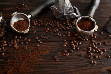 Kahve çekirdekleri ile koyu kahverengi ahşap yüzeyüzerinde portafilters ile Gayzer kahve makinesi