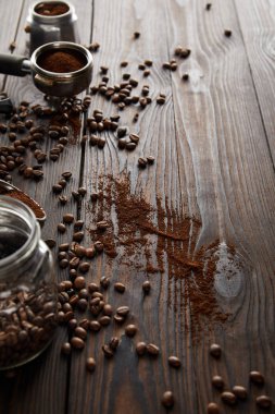 Portafilter ve kahve çekirdekleri ile koyu ahşap yüzeyüzerinde gayzer kahve makinesi parçası yakınında Cam kavanoz