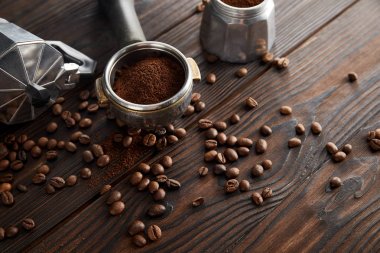 Kahve çekirdekleri ile koyu kahverengi ahşap yüzeyüzerinde portafilter yakın Gayzer kahve makinesi