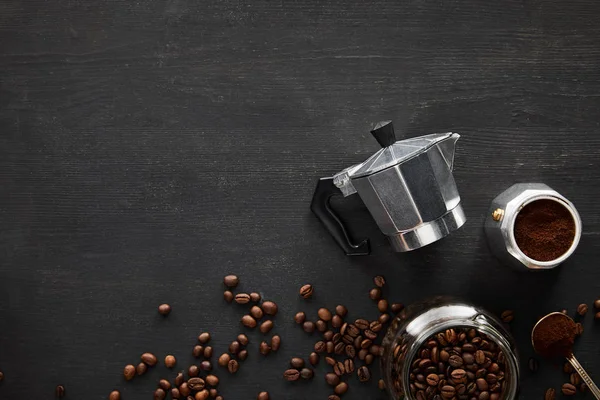コーヒー豆と暗い木製の表面にスプーンとガラス瓶の近くの間欠泉コーヒーメーカーの部品のトップビュー — ストック写真