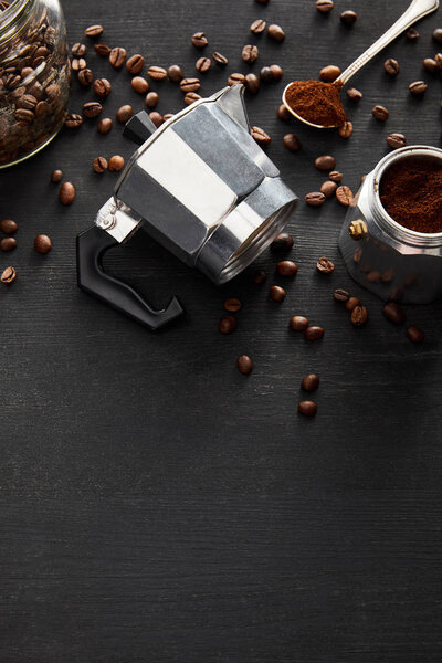 Separated parts of geyser coffee maker near glass jar and spoon on dark wooden surface with coffee beans