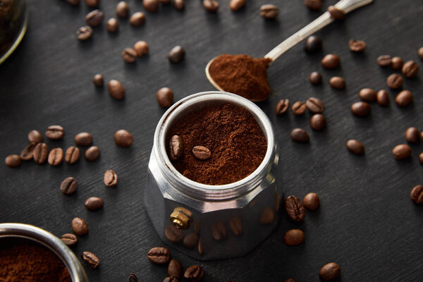 Part of geyser coffee maker with ground coffee near spoon on dark wooden surface with coffee beans