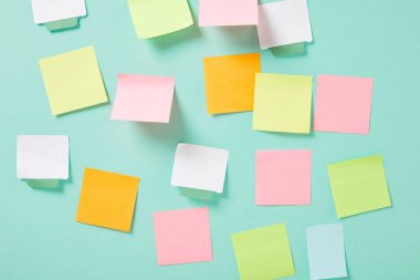 multicolored empty sticky notes with copy space on turquoise wall clipart