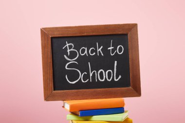 chalkboard with back to school words on stack of books isolated on pink clipart