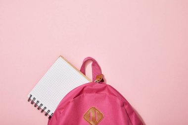 top view of blank notebook near backpack isolated on pink clipart