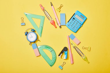 top view of school supplies scattered on yellow background clipart
