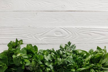 Beyaz beyaz ahşap yüzey üzerinde yeşil fesleğen, kişniş, maydanoz ve nane demetleri üst görünümü