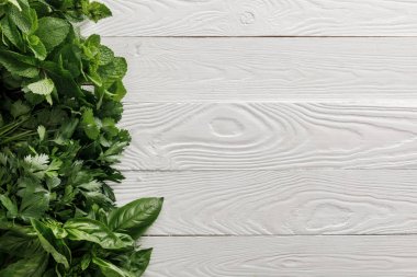 Beyaz beyaz ahşap yüzeyüzerinde fesleğen, kişniş, maydanoz ve nane demetleri üst görünümü