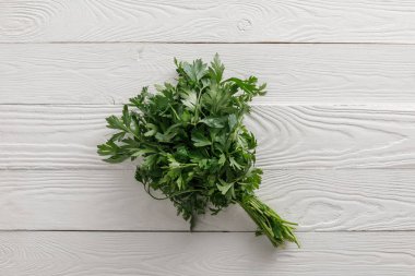Top view of fresh green parsley bundle on white wooden surface clipart