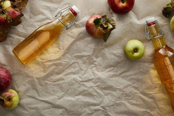 top view of bottles with cider near scattered apples with copy space