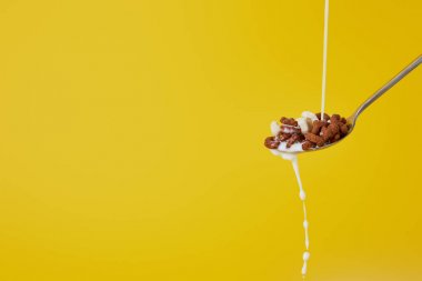 spoon with assorted cereal and milk stream isolated on yellow clipart