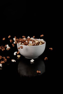 white bowl with cereal and dropped pieces isolated on black clipart