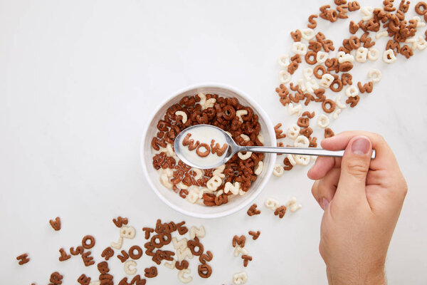 cropped image of man holding spoon with milk and cereal wow inscription above bowl on marble surface