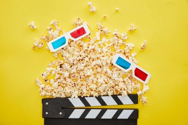 top view of delicious popcorn, 3d glasses and clapper board on yellow background clipart