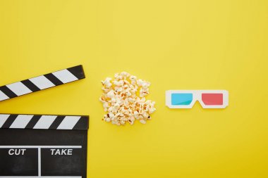top view of delicious popcorn near 3d glasses and clapper board on yellow background clipart