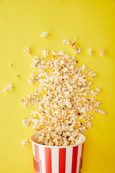 Top Uitzicht Van Heerlijke Popcorn Verspreid Van Emmer Gele Achtergrond — Stockfoto