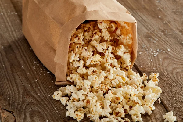 Deliciosas Palomitas Maíz Esparcidas Bolsa Papel Sobre Fondo Madera —  Fotos de Stock