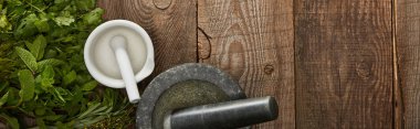 panoramic shot of white and grey mortars with pestles on wooden surface with fresh herbs clipart