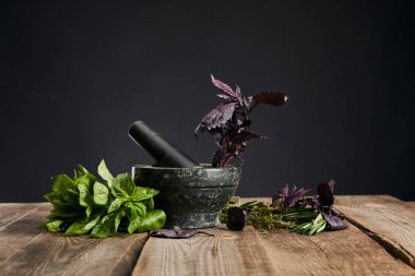 siyah izole ahşap masa üzerinde taze yeşil ve mor fesleğen yakın havaneli ile harç