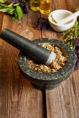 mortars with pestles with herbal mix on wooden surface clipart