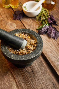 mortars with pestles with herbal mix near fresh basil on wooden surface clipart