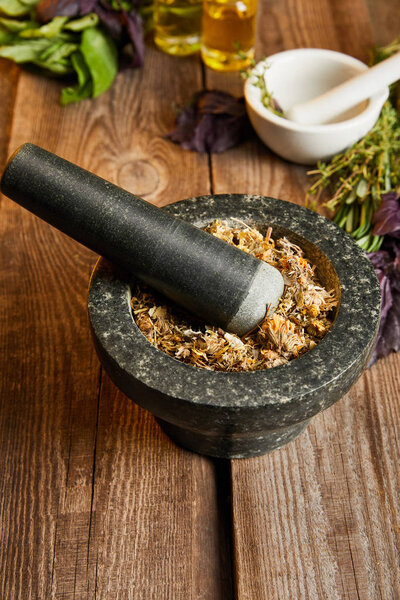 mortars with pestles with herbal mix on wooden surface