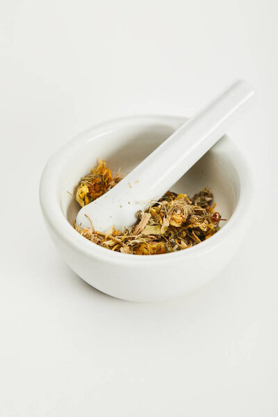 mortar and pestle with herbal tea blend on white background