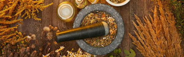 panoramic shot of grey mortar with herbal mix and pestle on wooden table