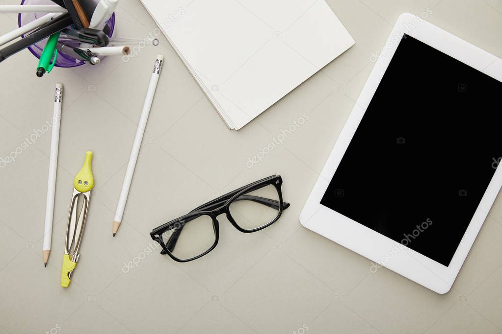 top view of digital tablet with blank screen near stationery and glasses isolated on grey 