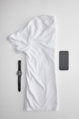 beyaz arka plan üzerinde saatler ve akıllı telefon yakın yarım t-shirt katlanmış boş yatıyordu düz