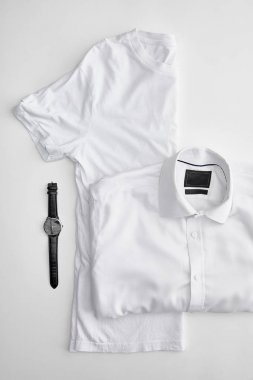 ekose gömlek ve beyaz arka plan üzerinde saatler yakın yarım t-shirt katlanmış üst görünümü