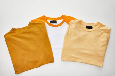 beyaz arka plan üzerinde bej, ochre ve turuncu katlanmış t-shirt üst görünümü