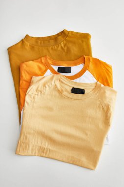 beyaz arka plan üzerinde bej, turuncu ve ochre katlanmış t-shirt üst görünümü