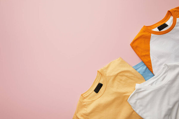 top view of color folded t-shirts on pink background