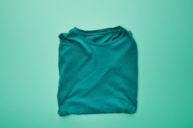 top view of blank color folded t-shirt on turquoise background clipart