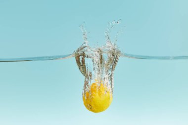 taze limon mavi arka plan üzerinde sıçrama ile su derin düşen