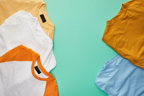 top view of diverse folded t-shirts on turquoise background