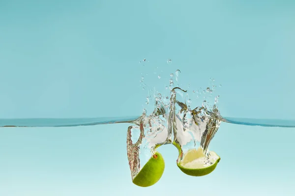 Ripe Lime Halves Falling Water Splashes Blue Background — Stock Photo, Image