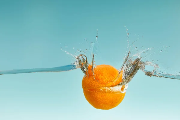 Geschnittene Orange Die Ins Wasser Fällt Mit Spritzern Auf Blauem — Stockfoto