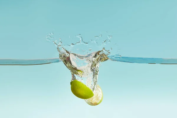 Ripe Lime Halves Falling Deep Water Splash Blue Background — Stock Photo, Image