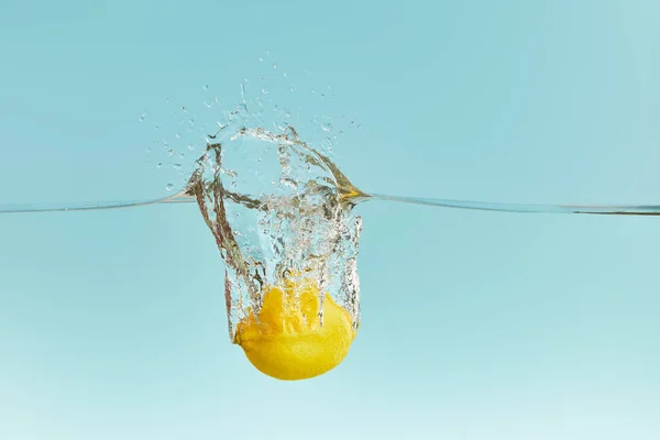 Свежий Желтый Лимон Падает Глубоко Воду Брызгами Синем Фоне — стоковое фото