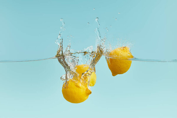 lemons falling deep in water with splash on blue background