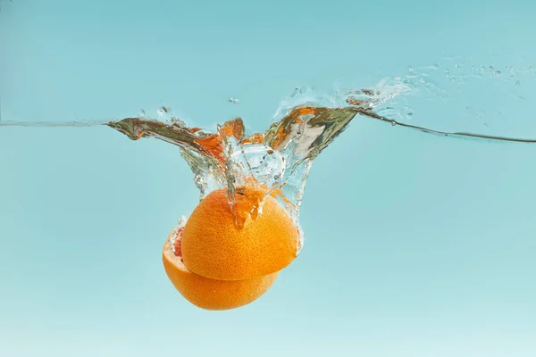Frische Orangefarbene Hälften Die Auf Blauem Hintergrund Ins Wasser Fallen — Stockfoto
