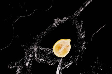 siyah izole berrak su sıçraması ile olgun limon yarım üst görünümü